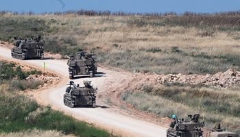 An invading Israeli military artillery unit drives across the border into Lebanon on May 27 [Rami...