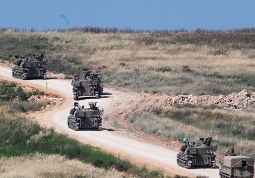 An invading Israeli military artillery unit drives across the border into Lebanon on May 27 [Rami...