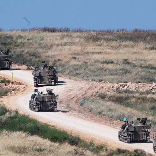 An invading Israeli military artillery unit drives across the border into Lebanon on May 27 [Rami...